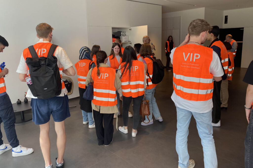 Erstsemester-Studierende bei der Werksbesichtigung bei Mercedes Benz werden mit Warnwesten ausgestattet